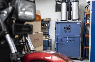 Blue Mil-tek baler in a small workshop with a motorcycle parked in front