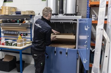 Man filling cardboard in a baler